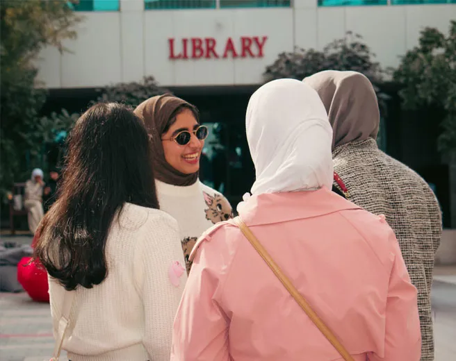 AUK students chatting in front of the AUK library.