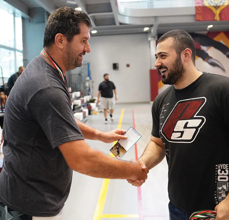 Two AUK faculty members shaking hands, reflecting collaboration and professional engagement