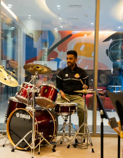 A talented AUK student practicing drums passionately, preparing for an exhilarating college event.