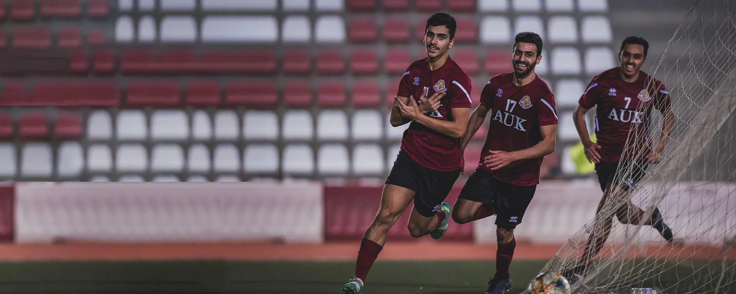 AUK football players in action on the field, representing the university their team uniform.
