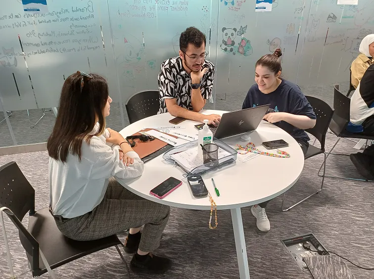 Three AUK faculty members deeply engrossed in a meaningful conversation, fostering intellectual exchange.