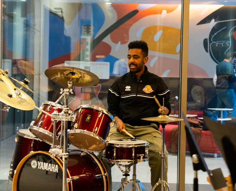 A talented AUK student practicing drums passionately, preparing for an exhilarating college event.