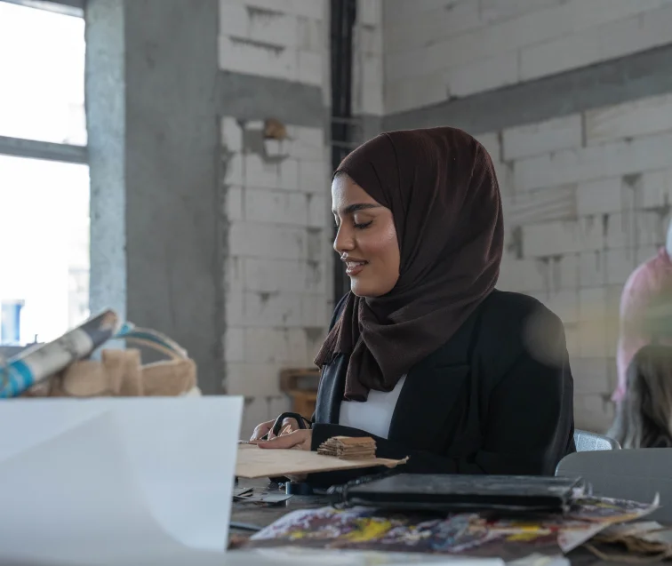 A student cutting a piece of paper with scissors, involved in a hands-on project at AUK.
