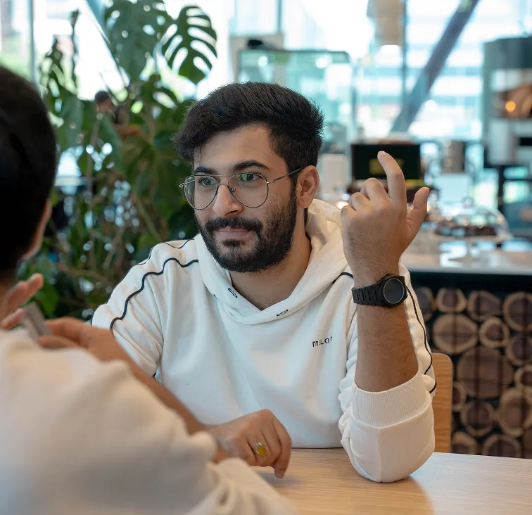 Two AUK alumni sitting together in the university cafeteria, engaged in a lively conversation.