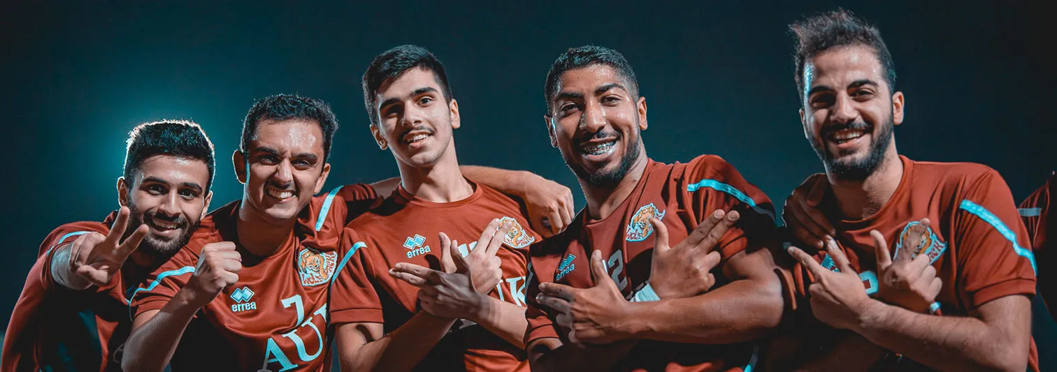 Five AUK football team members proudly posing together in their team uniforms.