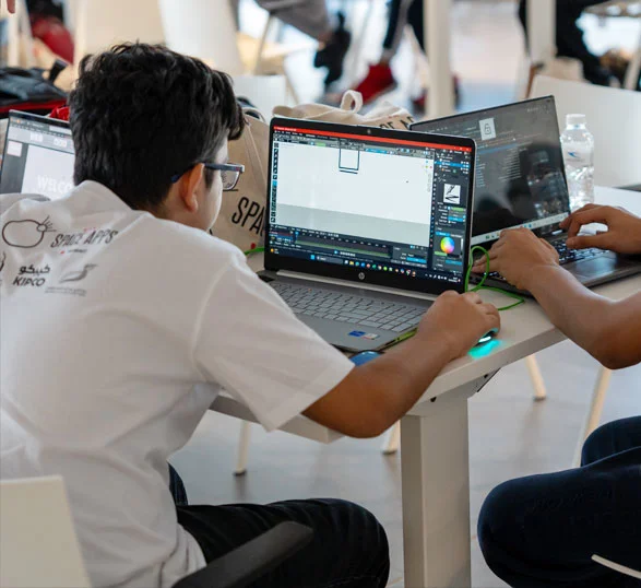 AUK students collaborating on a project, working together on a laptop