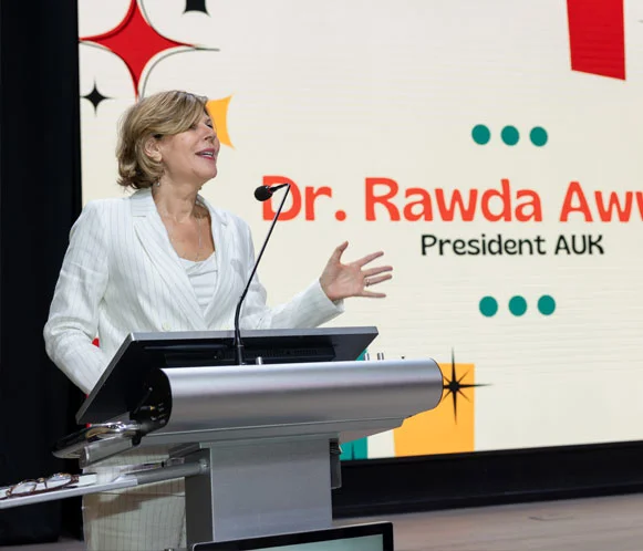 Dr. Radwa, President of AUK, delivering an inspiring speech on stage.