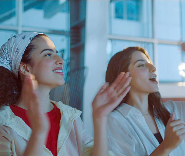 Two AUK supporters cheering for their team from the sidelines.