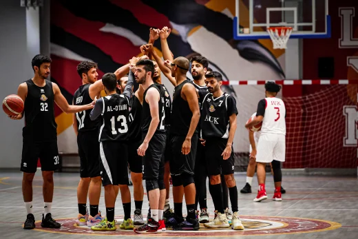 Basketball players at AUK energizing the court, cheering for each other during a spirited game.