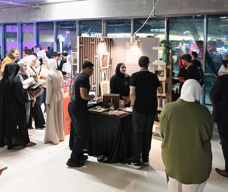 A vibrant event hosted by The American University Of Kuwait - AUK, with a group of people gathered and interacting.